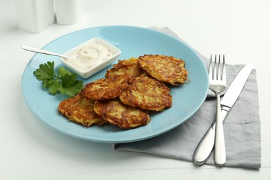 Photo of Delicious potato pancakes served on white wooden table, closeup