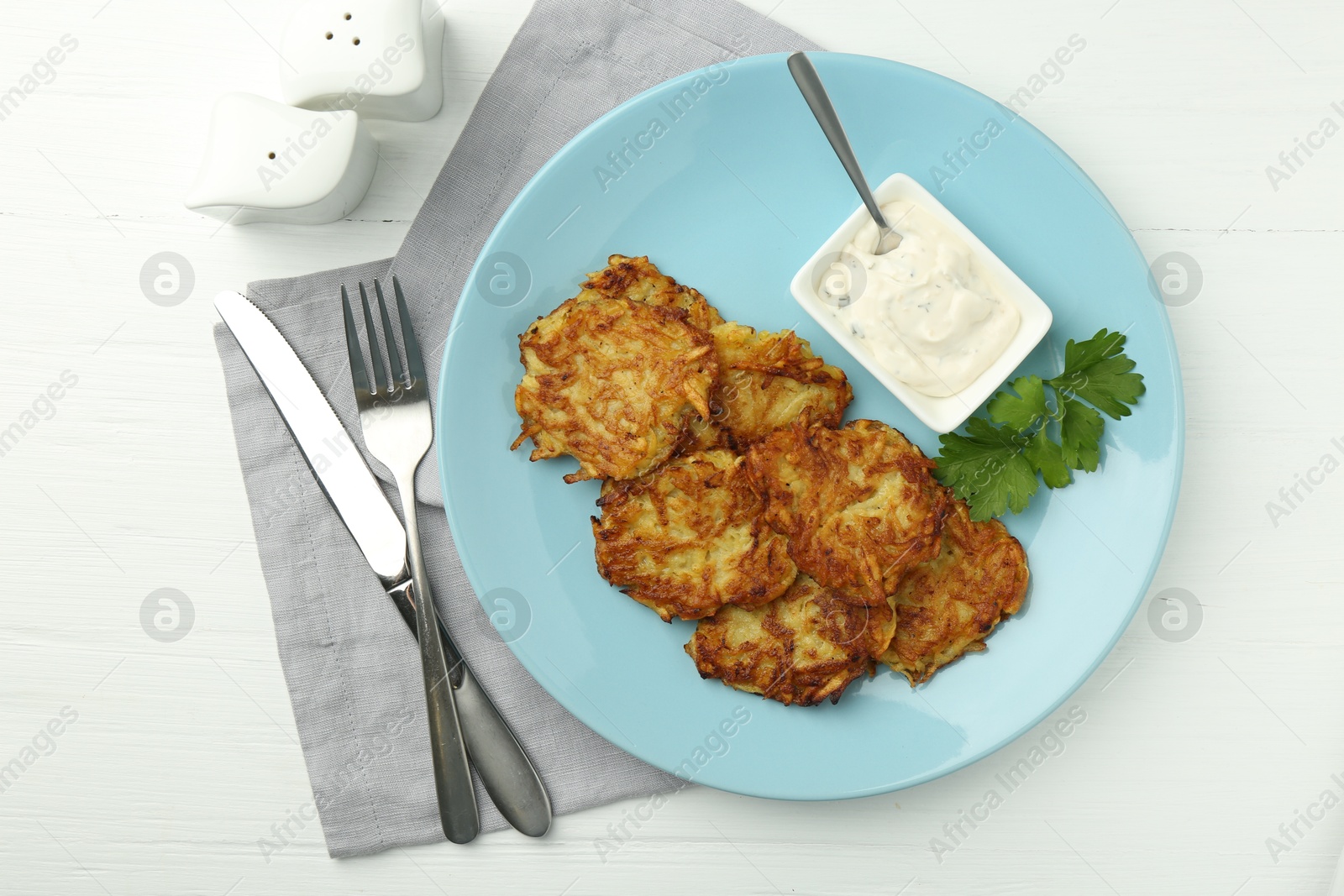 Photo of Delicious potato pancakes served on white wooden table, flat lay