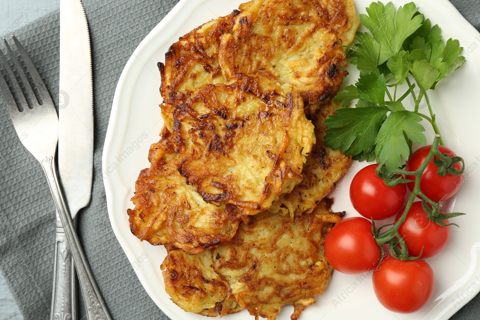 Photo of Delicious potato pancakes with tomatoes and parsley served on table, flat lay