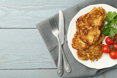 Photo of Delicious potato pancakes with tomatoes and parsley served on gray wooden table, flat lay. Space for text