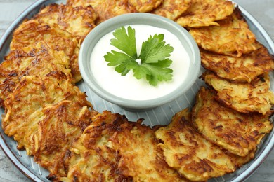 Photo of Delicious potato pancakes and sour cream on plate, closeup