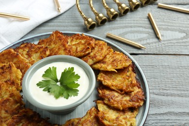 Photo of Delicious potato pancakes, menorah and candles on gray wooden table, closeup. Hanukkah festive food