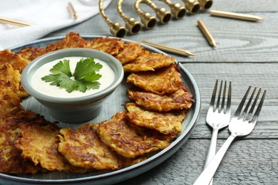 Photo of Delicious potato pancakes served on gray wooden table, closeup. Hanukkah festive food