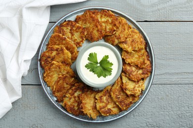 Photo of Delicious potato pancakes and sour cream on gray wooden table, top view