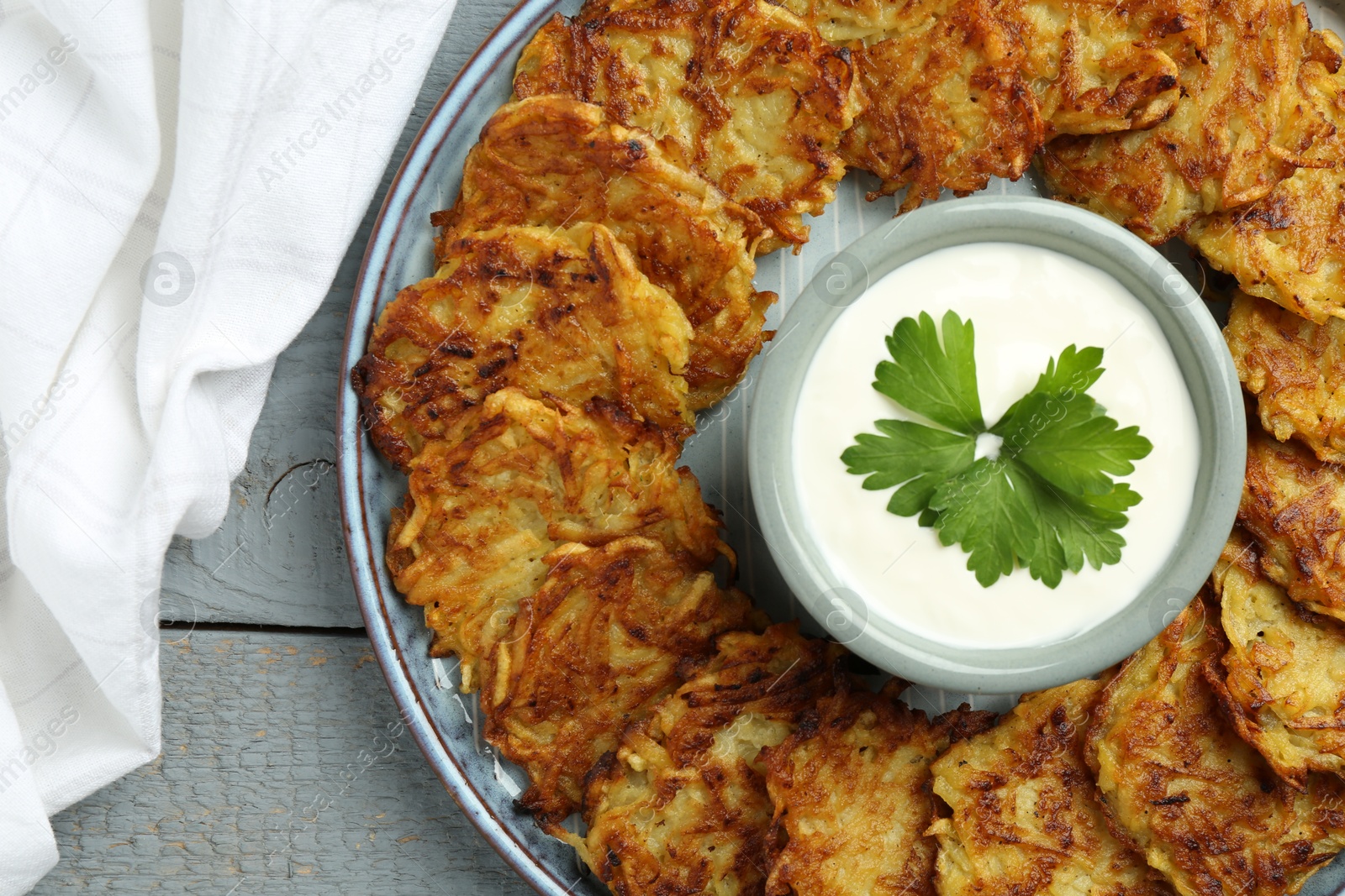 Photo of Delicious potato pancakes and sour cream on gray wooden table, top view