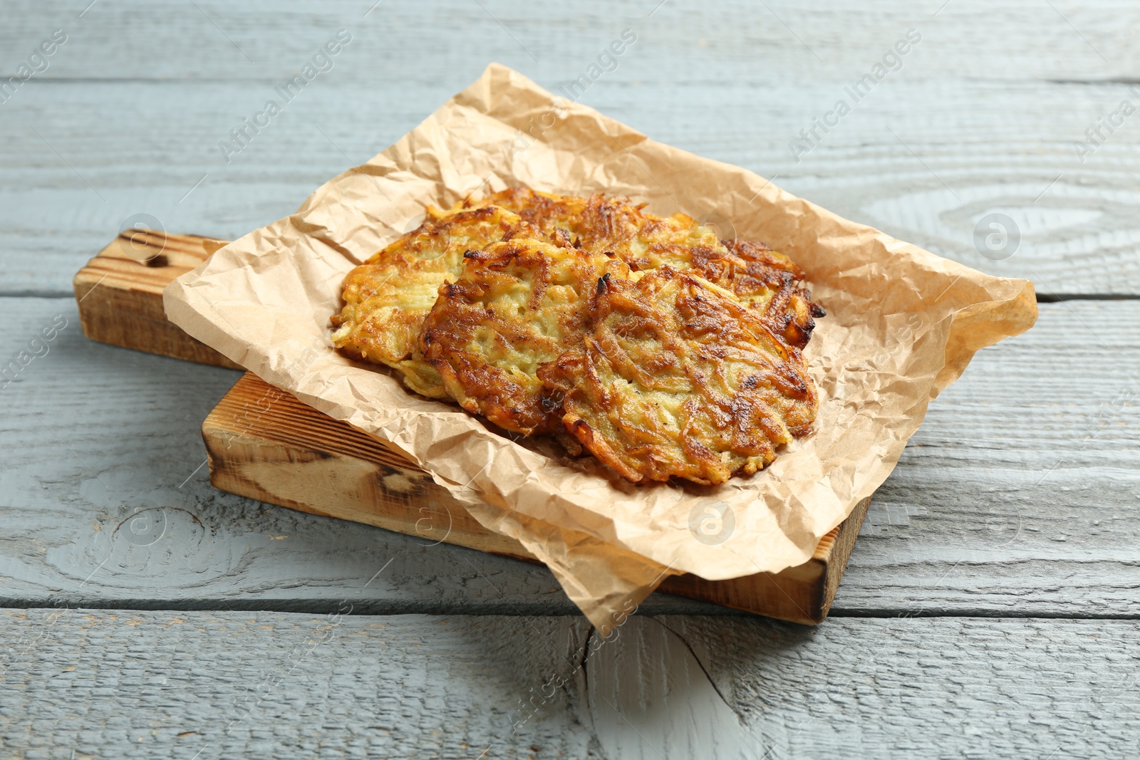 Photo of Delicious potato pancakes on grey wooden table, closeup