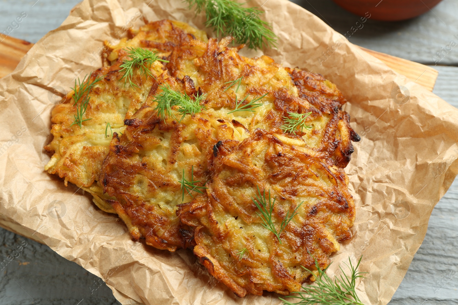 Photo of Delicious potato pancakes with dill on grey wooden table, closeup