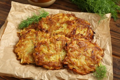 Photo of Delicious potato pancakes with dill on wooden table, closeup