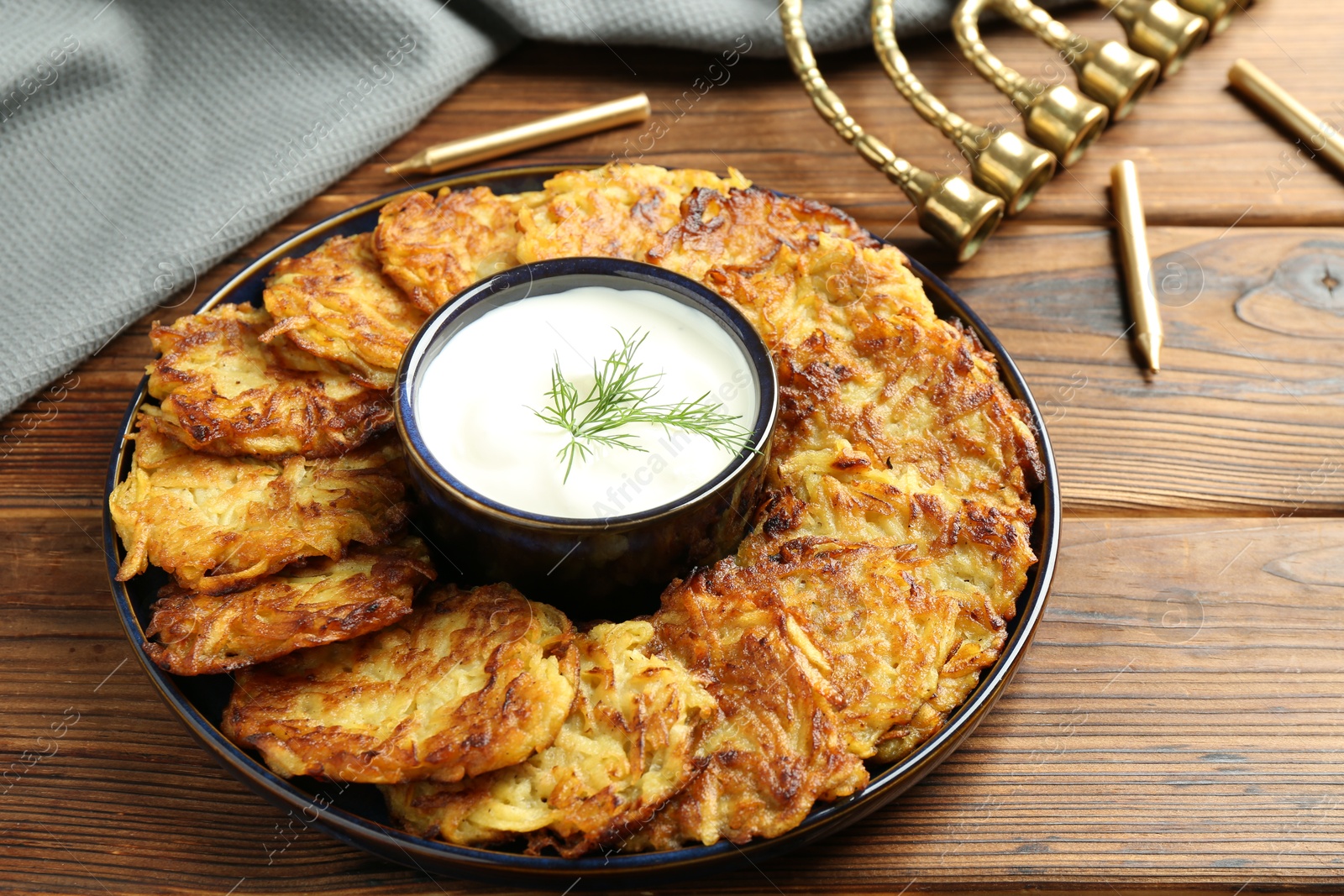 Photo of Delicious potato pancakes with sour cream on wooden table