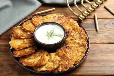 Delicious potato pancakes with sour cream on wooden table