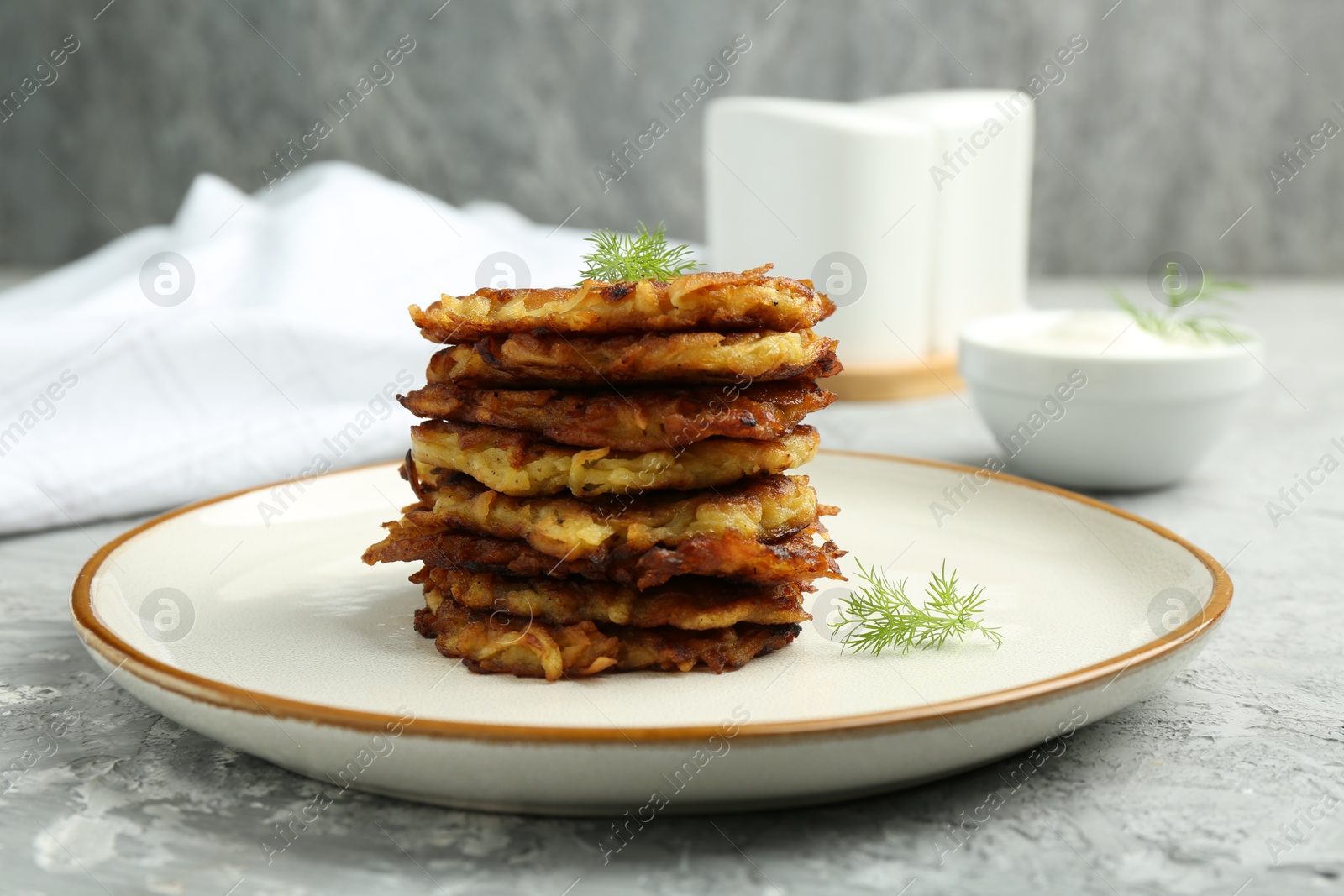 Photo of Delicious potato pancakes with fresh dill on grey textured table, closeup