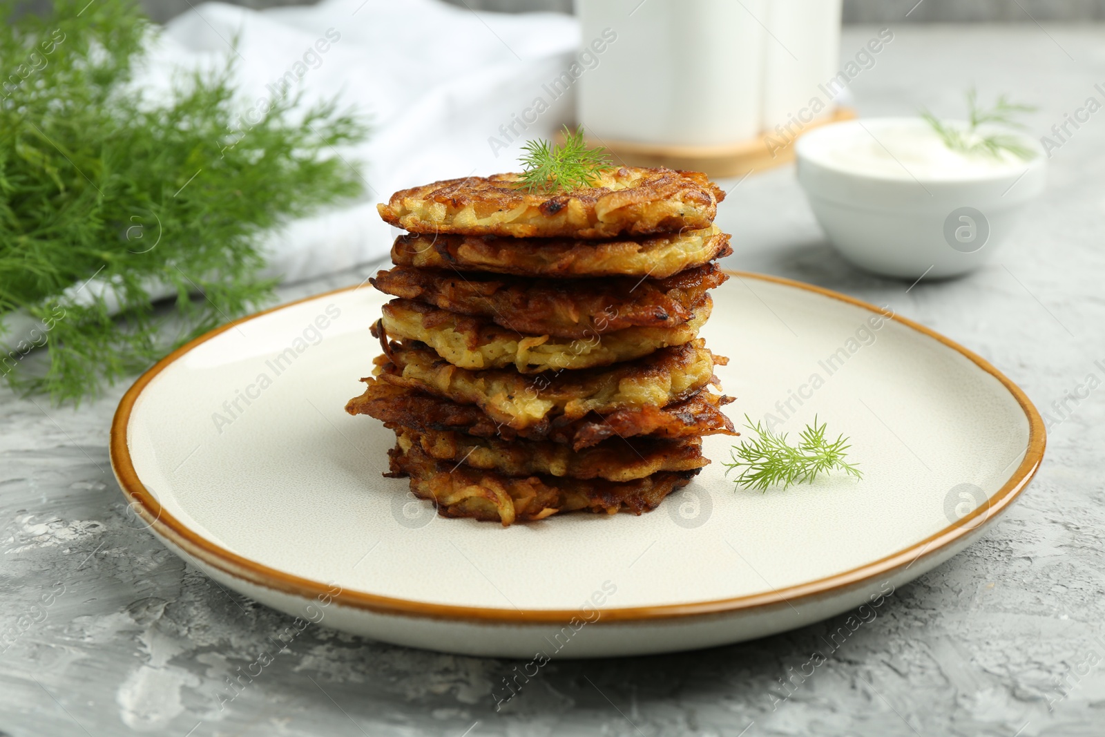 Photo of Delicious potato pancakes with fresh dill on grey textured table, closeup