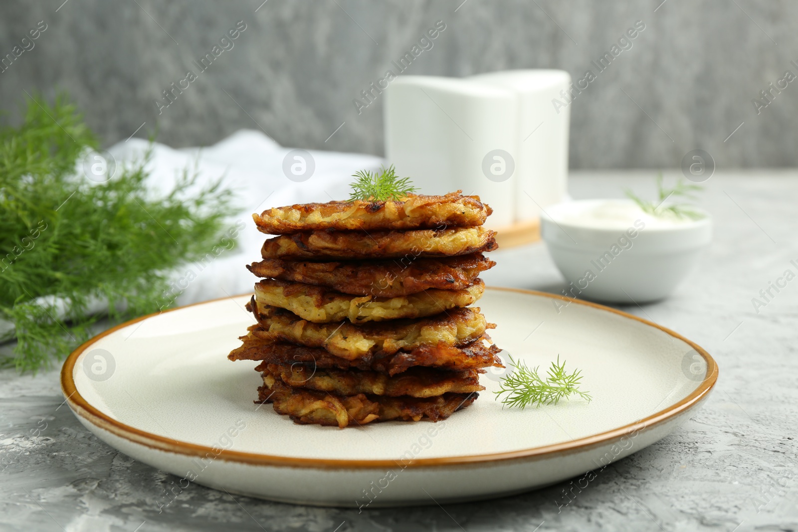 Photo of Delicious potato pancakes with fresh dill on grey textured table, closeup