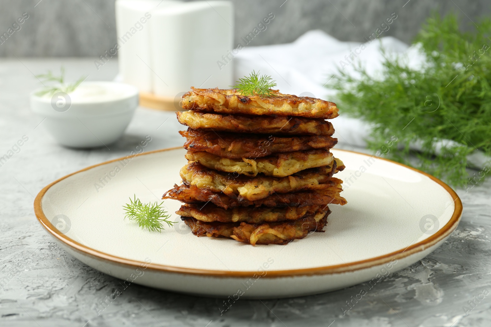 Photo of Delicious potato pancakes with fresh dill on grey textured table, closeup