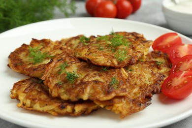 Photo of Delicious potato pancakes with fresh tomatoes and dill on table, closeup