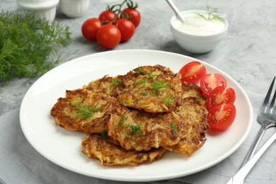 Photo of Delicious potato pancakes with fresh tomatoes served on grey table