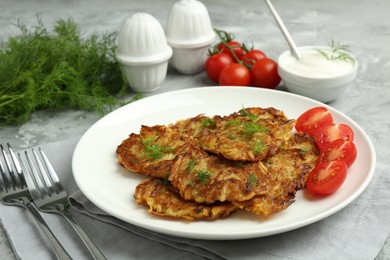 Photo of Delicious potato pancakes with fresh tomatoes served on grey table