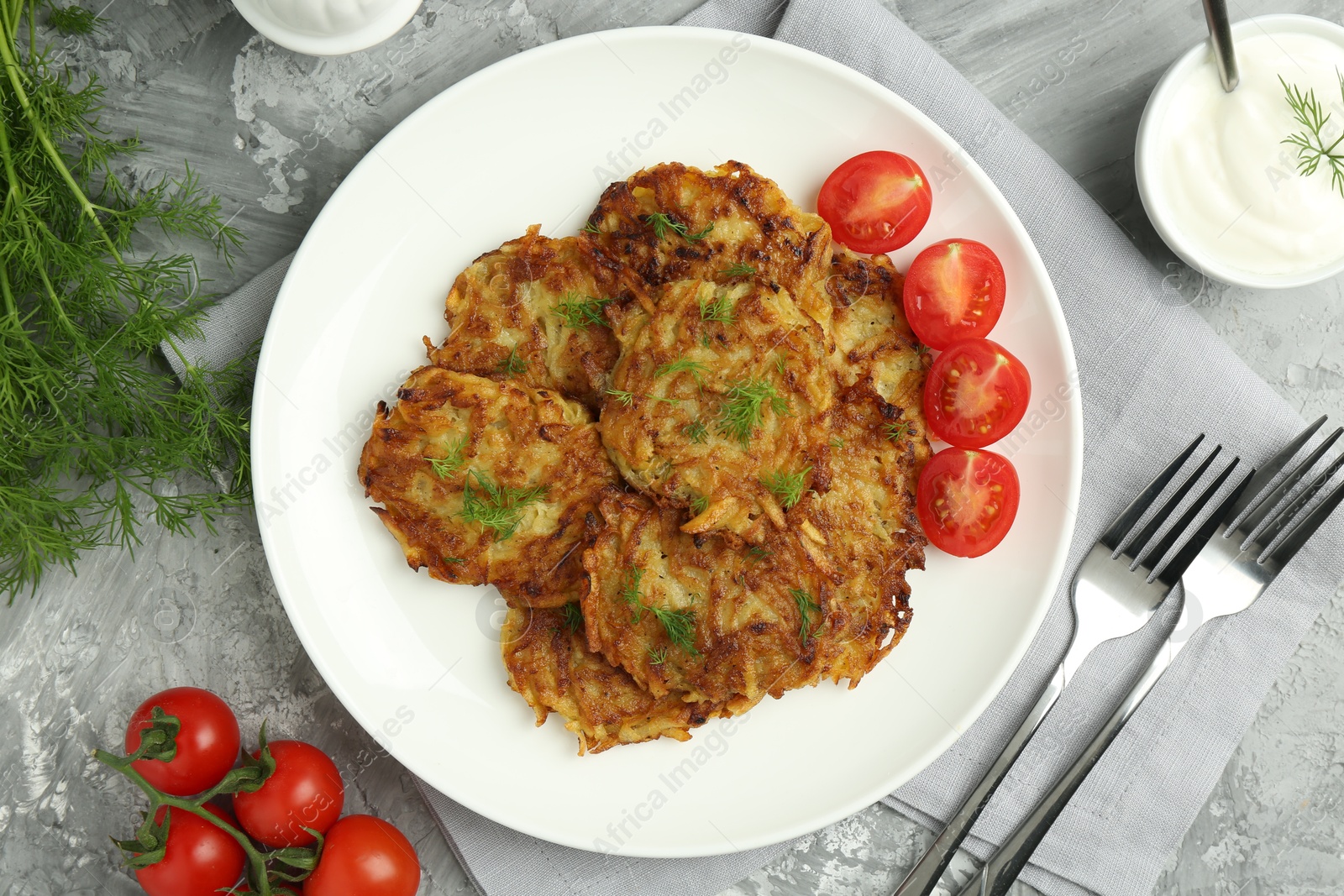 Photo of Delicious potato pancakes served on grey textured table, flat lay