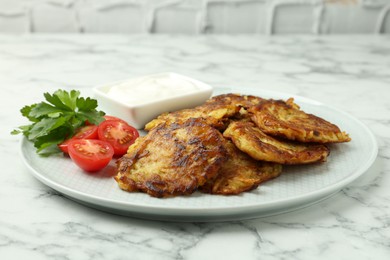 Delicious potato pancakes with fresh tomatoes, sour cream and parsley on white marble table, closeup