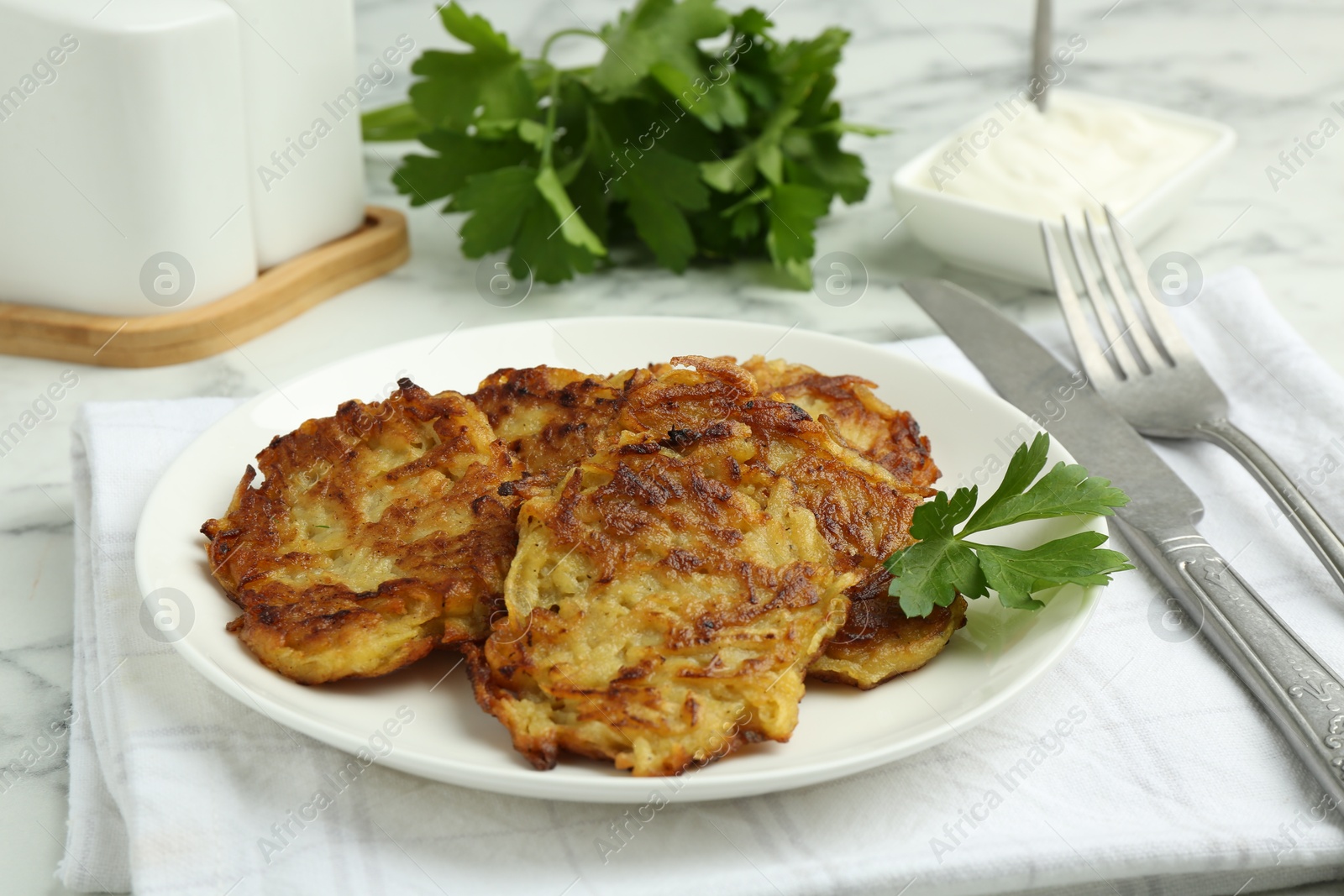 Photo of Delicious potato pancakes served on white marble table, closeup