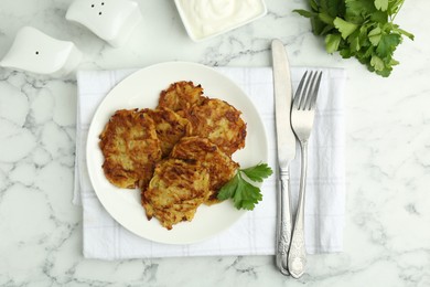 Photo of Delicious potato pancakes served on white marble table, flat lay