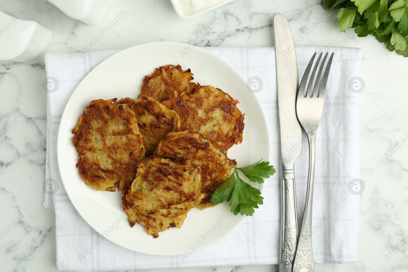 Photo of Delicious potato pancakes served on white marble table, flat lay