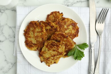 Photo of Delicious potato pancakes served on white marble table, flat lay