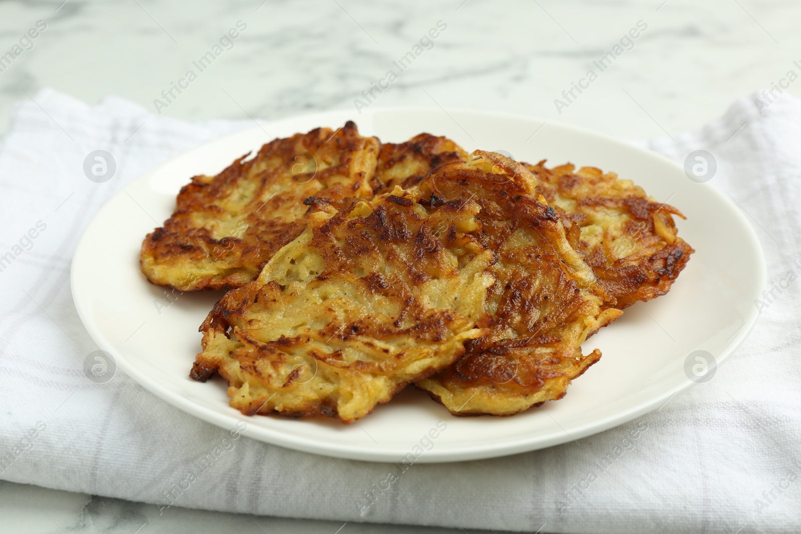 Photo of Delicious potato pancakes on white marble table, closeup