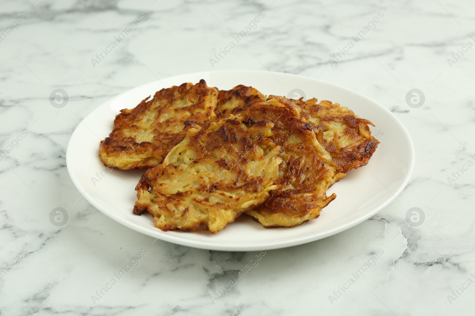 Photo of Delicious potato pancakes on white marble table, closeup