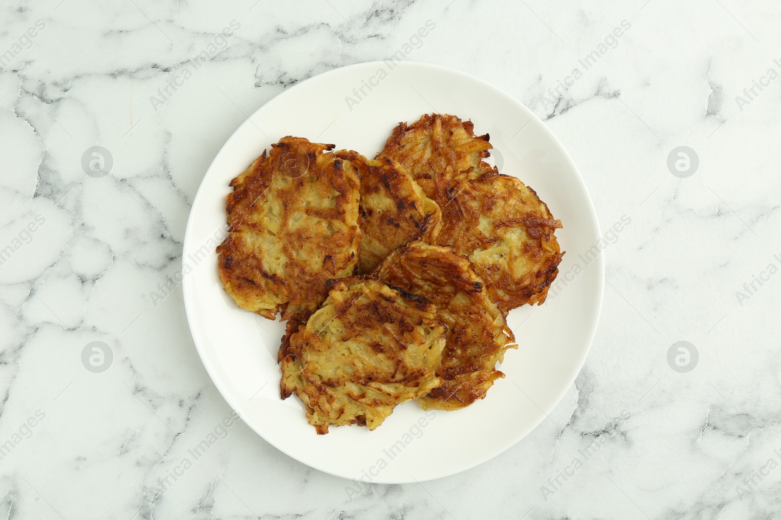 Photo of Delicious potato pancakes on white marble table, top view