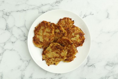 Photo of Delicious potato pancakes on white marble table, top view