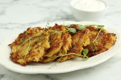 Photo of Delicious potato pancakes with fresh microgreens on white marble table, closeup