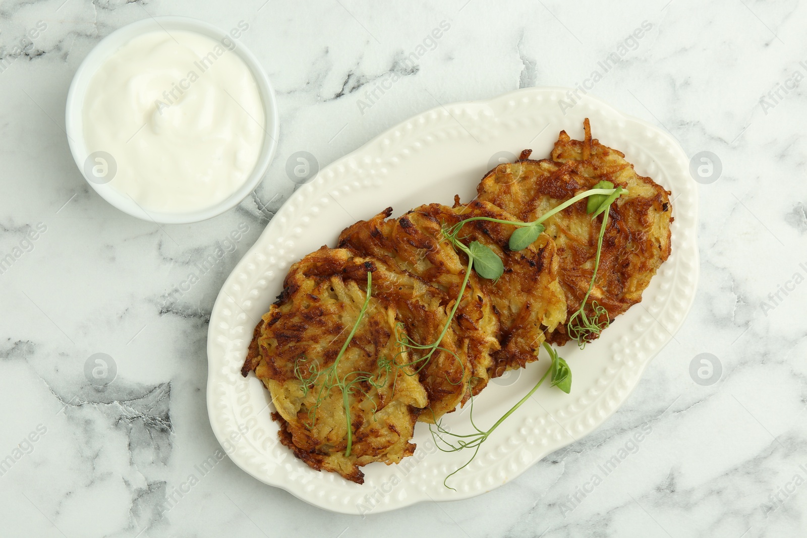 Photo of Delicious potato pancakes served on white marble table, flat lay