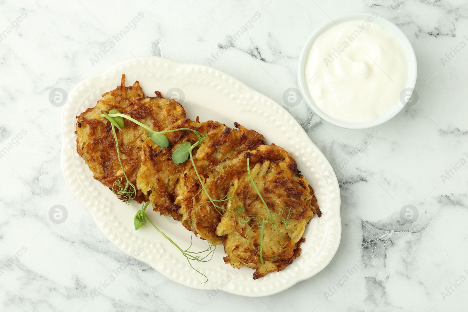 Photo of Delicious potato pancakes served on white marble table, flat lay