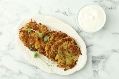 Delicious potato pancakes served on white marble table, flat lay