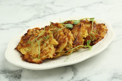 Photo of Delicious potato pancakes with microgreens on white marble table, closeup