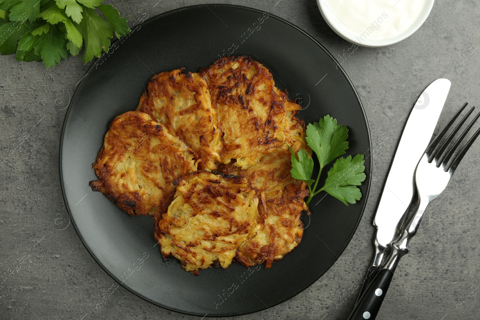 Photo of Delicious potato pancakes served on grey table, flat lay