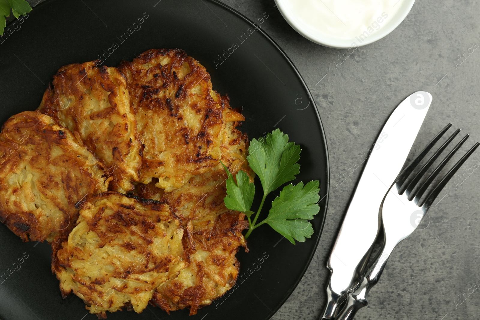 Photo of Delicious potato pancakes served on grey table, flat lay