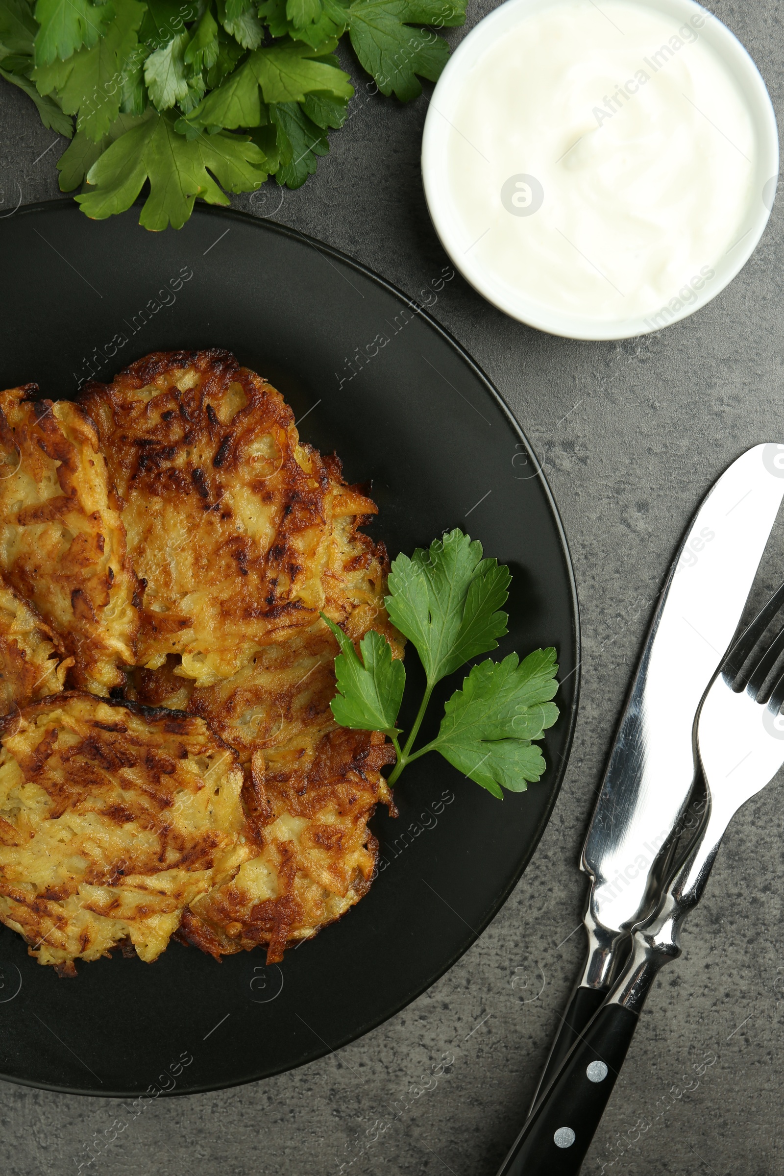 Photo of Delicious potato pancakes served on grey table, flat lay