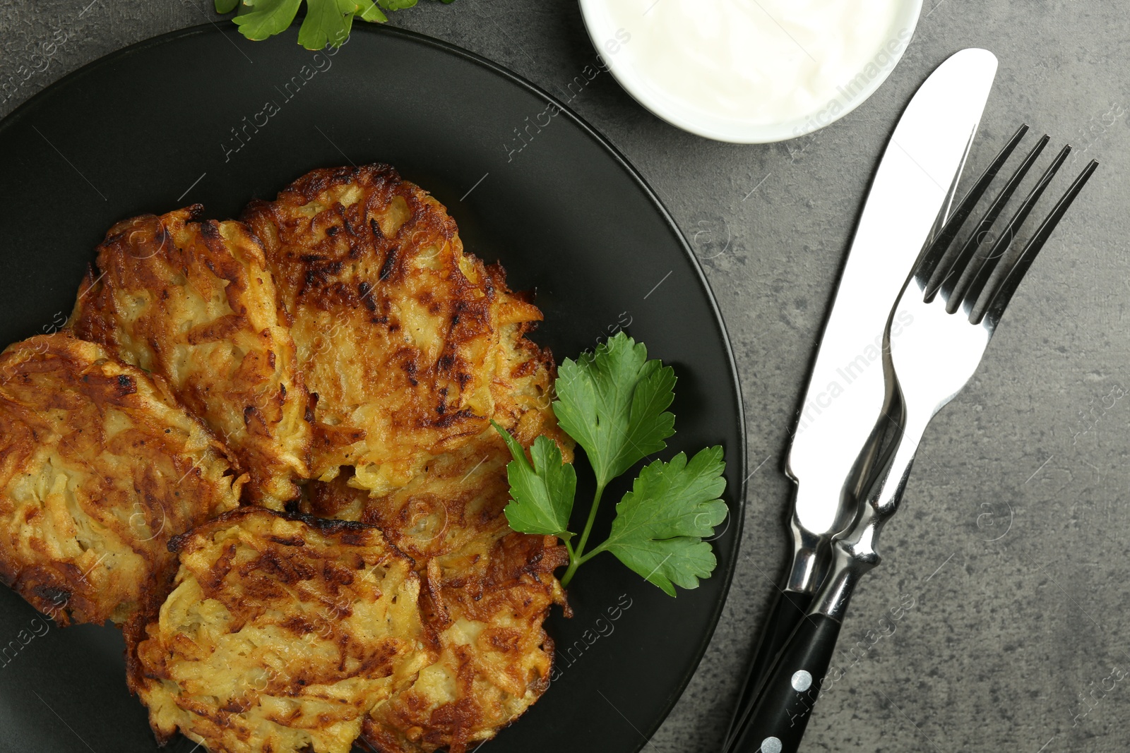 Photo of Delicious potato pancakes served on grey table, flat lay