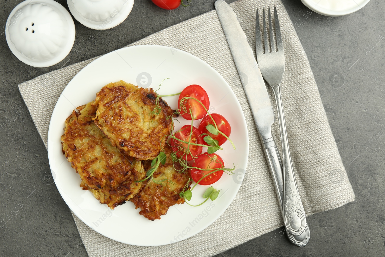 Photo of Delicious potato pancakes served on grey table, flat lay