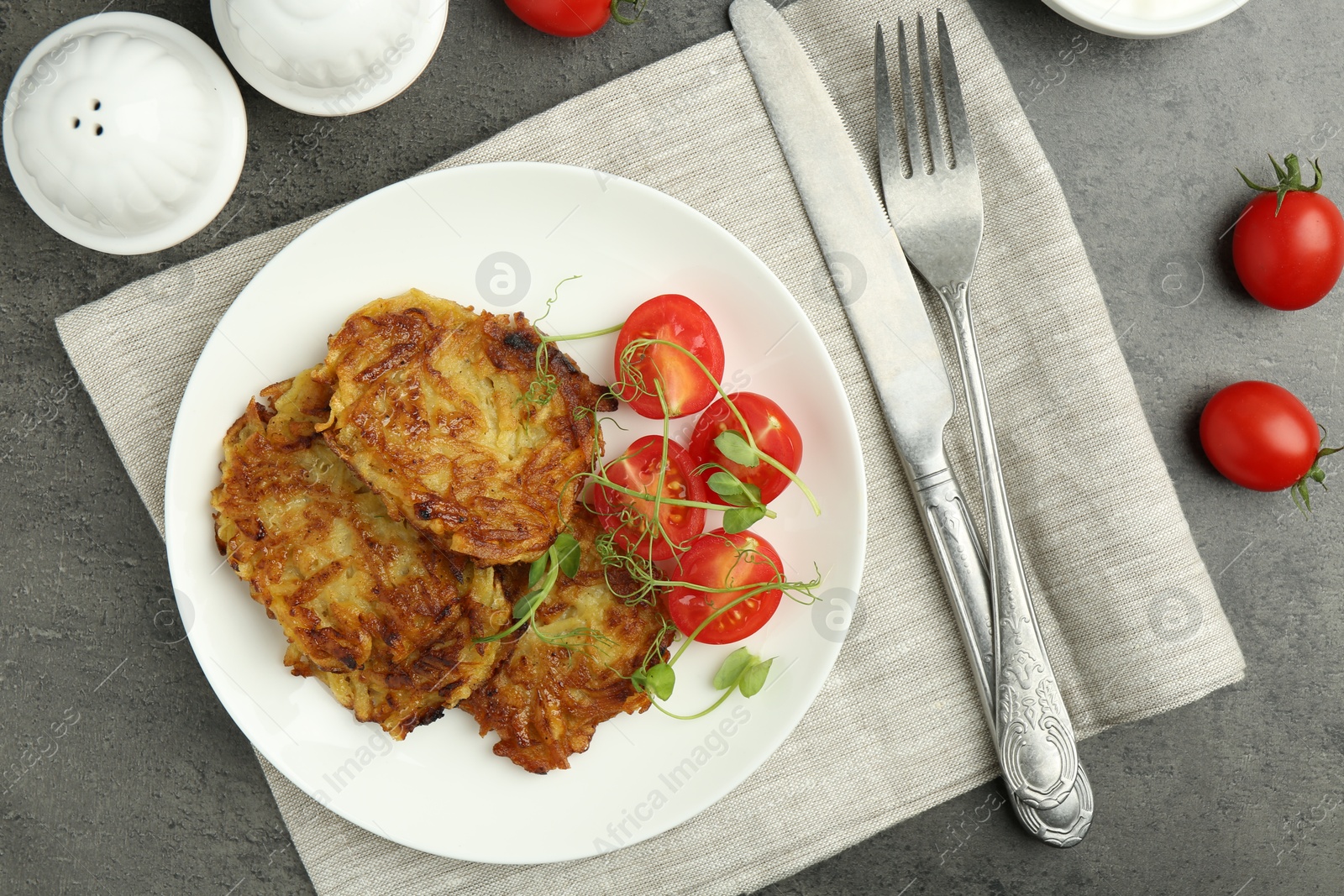 Photo of Delicious potato pancakes served on grey table, flat lay