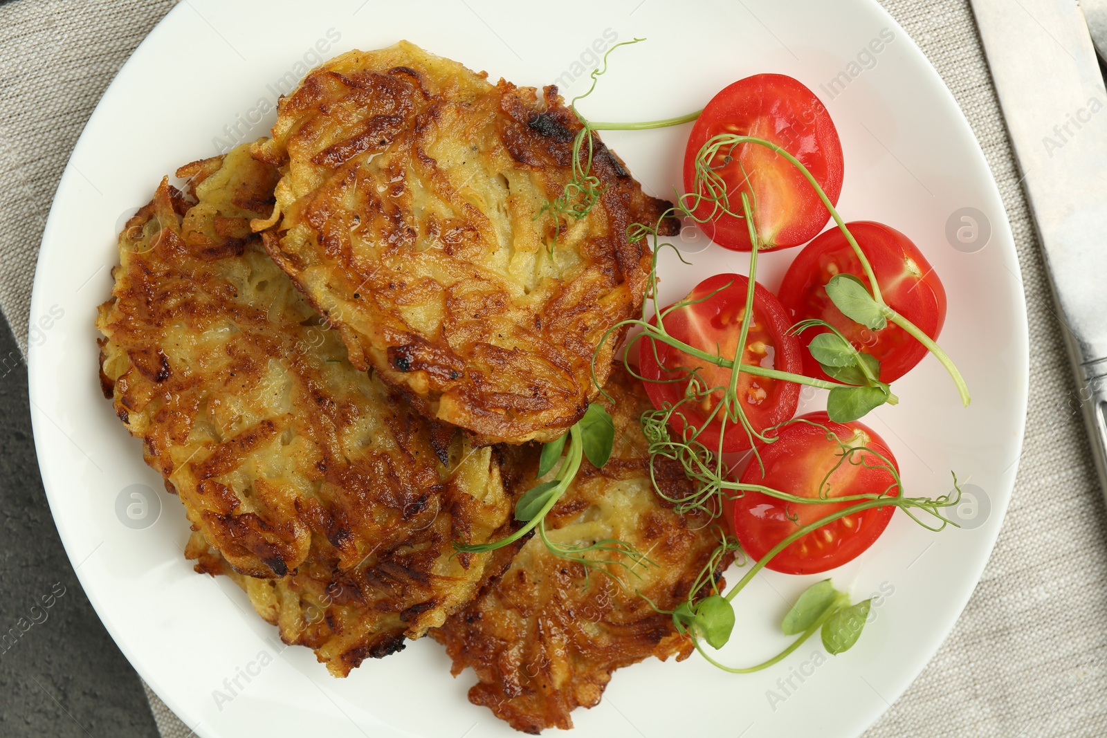 Photo of Delicious potato pancakes with fresh tomatoes and microgreens on grey table, top view