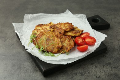 Photo of Delicious potato pancakes with fresh tomatoes and microgreens on grey table, closeup