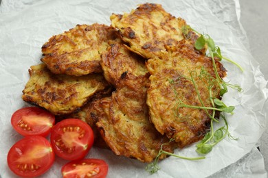 Photo of Delicious potato pancakes with fresh tomatoes and microgreens on table, closeup