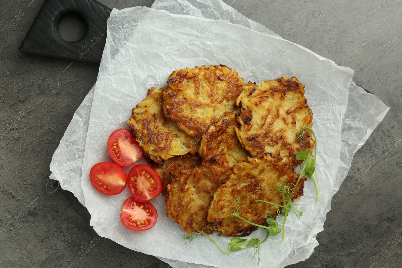 Photo of Delicious potato pancakes with fresh tomatoes and microgreens on grey table, top view