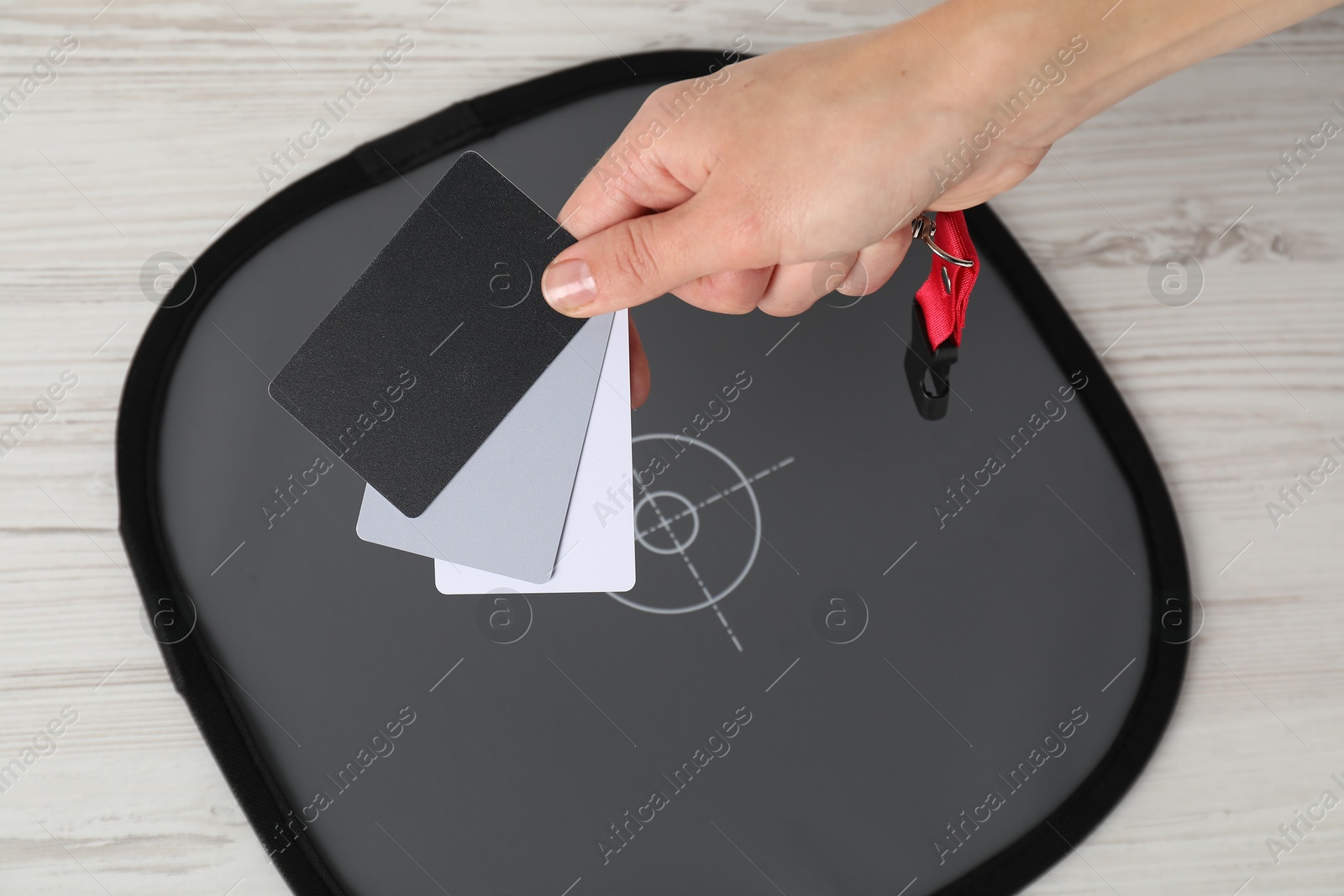 Photo of Woman with white balance calibration cards at wooden table, closeup