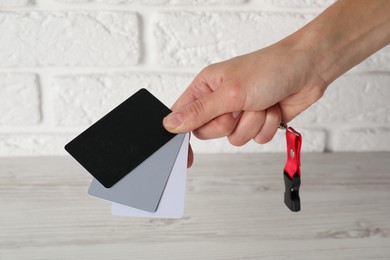 Photo of Woman with white balance calibration cards at wooden table, closeup