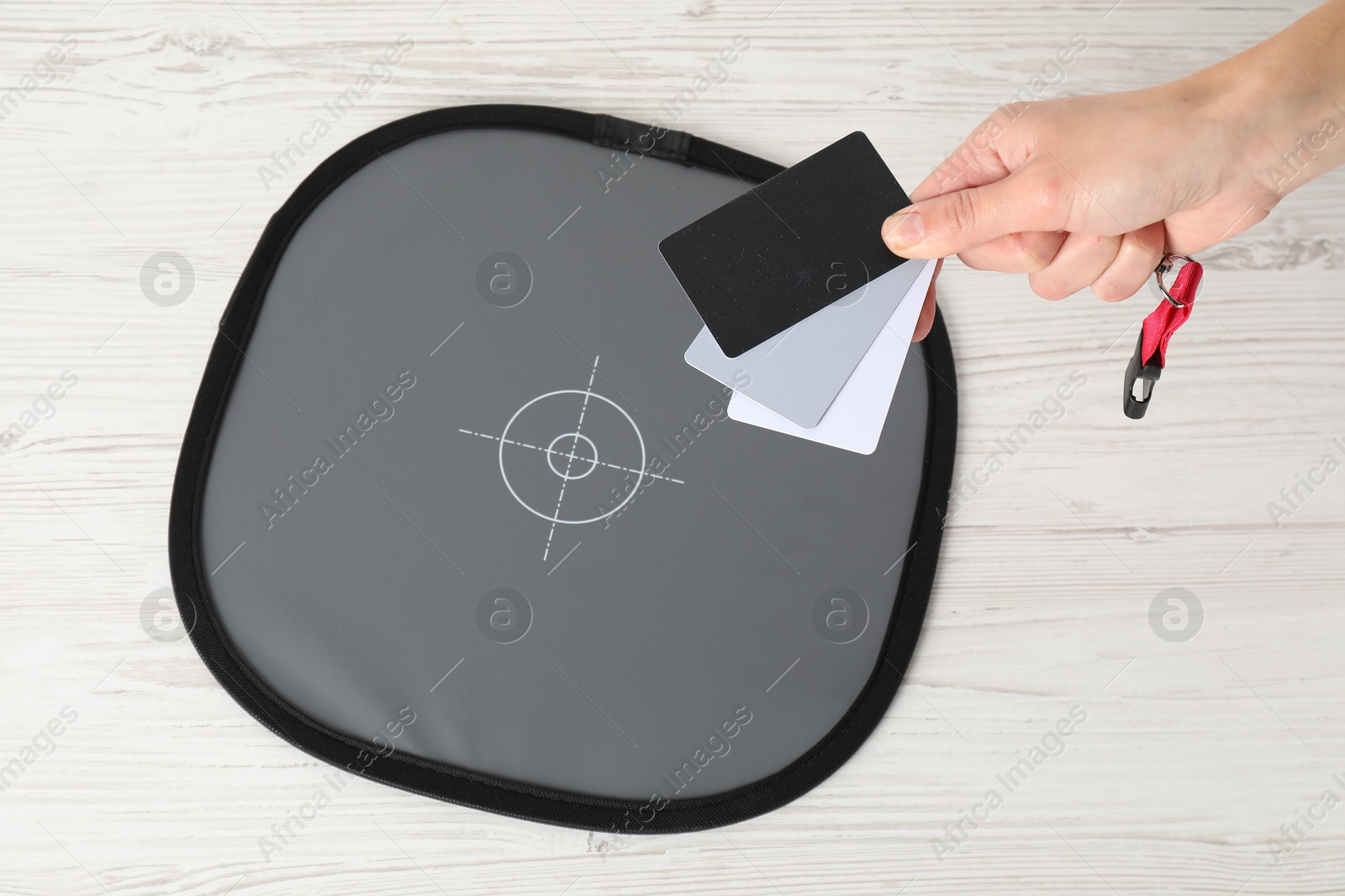 Photo of Woman with white balance calibration cards at wooden table, closeup