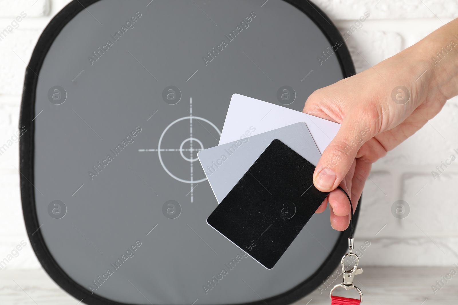 Photo of Woman with white balance calibration cards at wooden table, closeup